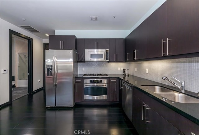 kitchen with dark countertops, visible vents, tasteful backsplash, stainless steel appliances, and a sink