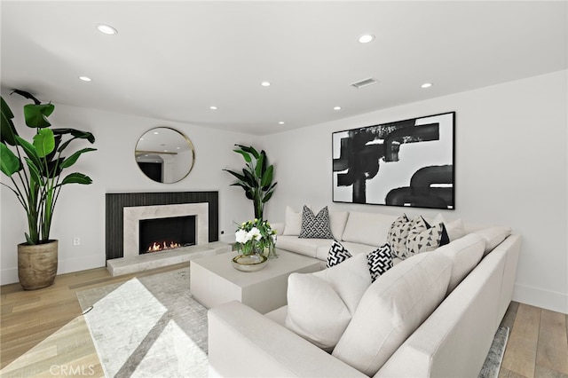 living room featuring recessed lighting, wood finished floors, a high end fireplace, baseboards, and visible vents