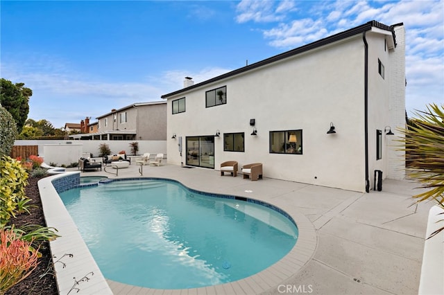 view of pool featuring a patio area, a pool with connected hot tub, outdoor lounge area, and fence