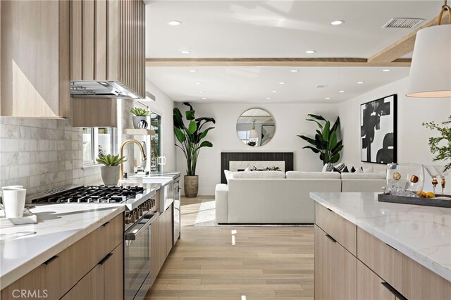 kitchen with light stone counters, modern cabinets, light brown cabinets, and high end stainless steel range