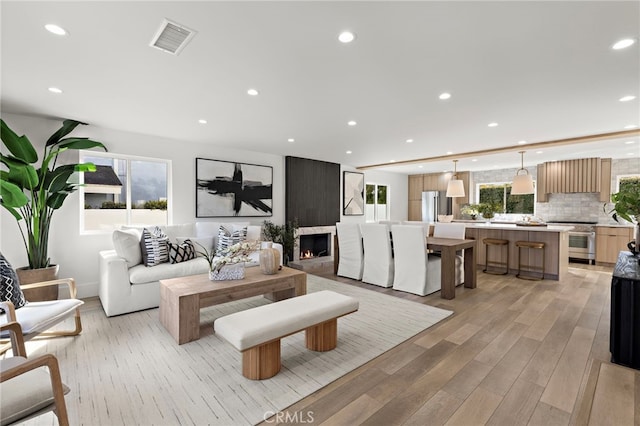 living room featuring visible vents, recessed lighting, a fireplace, and light wood-type flooring