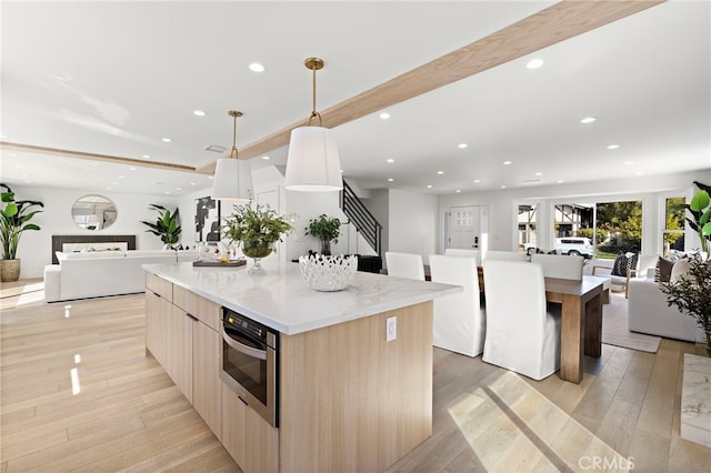 kitchen with stainless steel oven, a large island, modern cabinets, and open floor plan