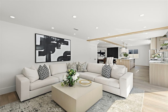 living area with baseboards, recessed lighting, visible vents, and light wood-style flooring