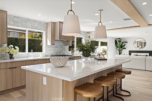 kitchen featuring modern cabinets, a kitchen breakfast bar, visible vents, backsplash, and a kitchen island