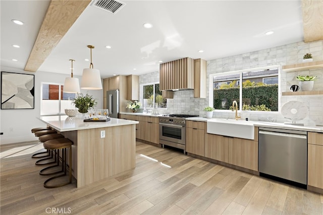 kitchen featuring a sink, high quality appliances, backsplash, and visible vents