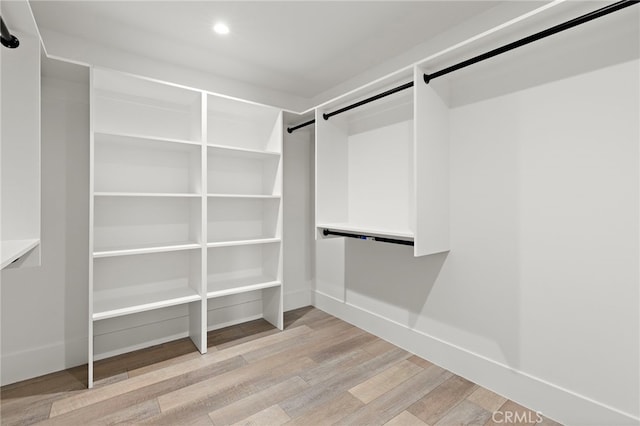 walk in closet featuring a barn door and light wood finished floors