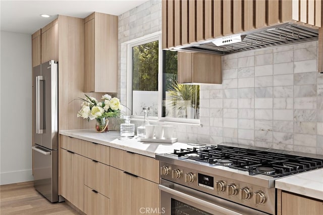 kitchen with light brown cabinets, light stone counters, tasteful backsplash, stainless steel appliances, and custom exhaust hood