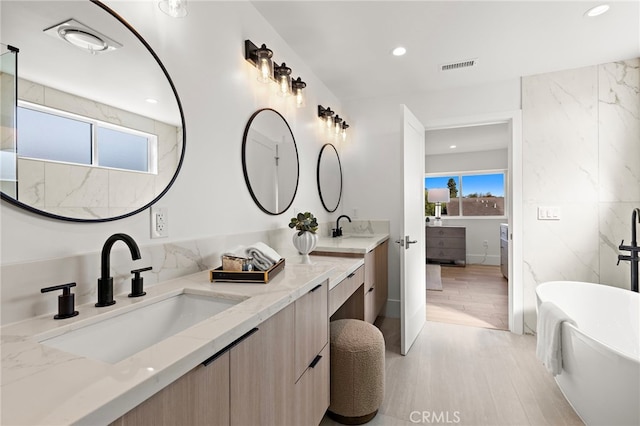 bathroom featuring double vanity, visible vents, plenty of natural light, and a sink