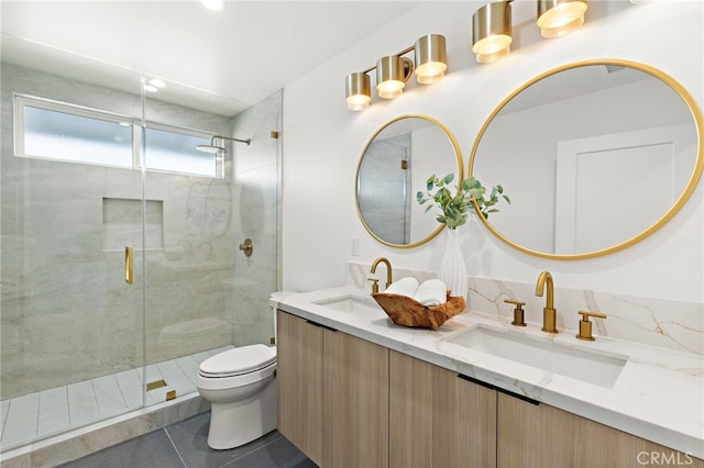 bathroom featuring double vanity, a shower stall, toilet, and a sink