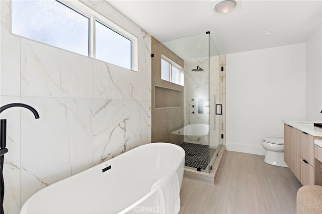 full bath with vanity, toilet, a marble finish shower, baseboards, and a soaking tub