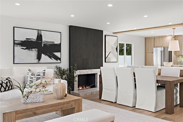 living room with a premium fireplace, recessed lighting, and light wood-style floors