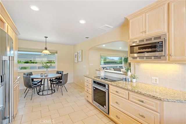 kitchen featuring tasteful backsplash, light brown cabinetry, light stone counters, appliances with stainless steel finishes, and arched walkways