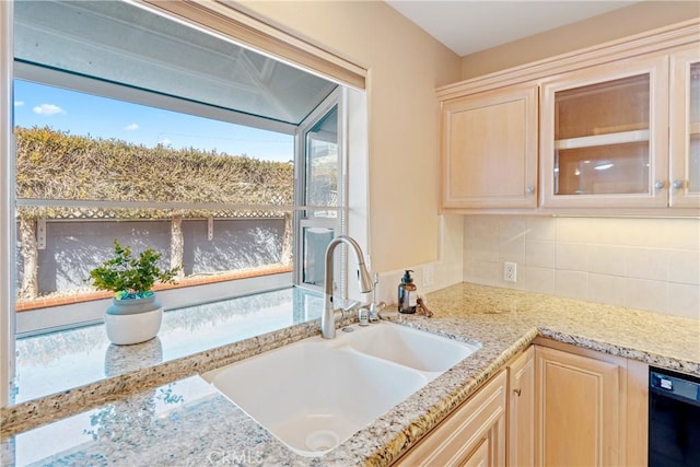 kitchen with light brown cabinetry, a sink, backsplash, glass insert cabinets, and dishwasher