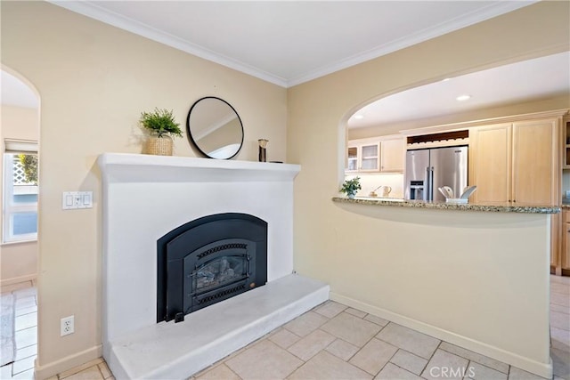 unfurnished living room featuring arched walkways, a glass covered fireplace, baseboards, and ornamental molding