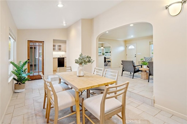 dining room with arched walkways, recessed lighting, baseboards, and stone tile flooring