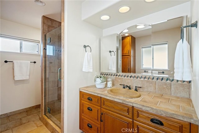 bathroom with vanity, a shower stall, a healthy amount of sunlight, and baseboards