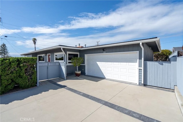 garage with a gate, concrete driveway, and fence