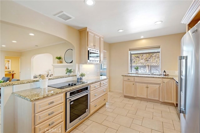 kitchen featuring light brown cabinetry, visible vents, backsplash, and stainless steel appliances