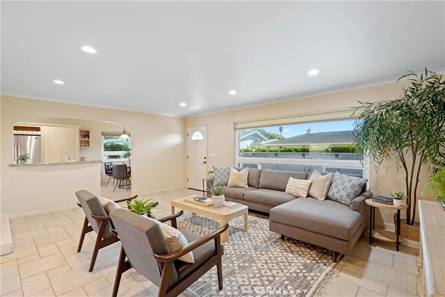 living room featuring arched walkways, recessed lighting, baseboards, and stone tile flooring