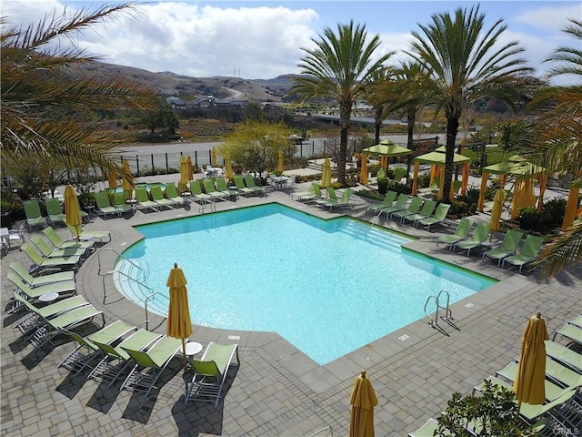 community pool featuring a mountain view, a patio, and fence