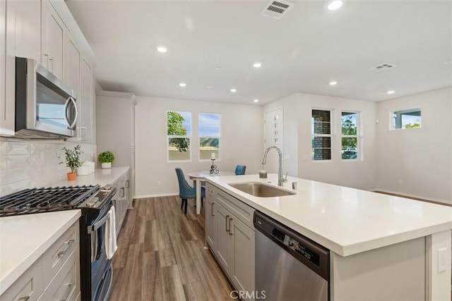 kitchen featuring tasteful backsplash, visible vents, appliances with stainless steel finishes, wood finished floors, and a sink