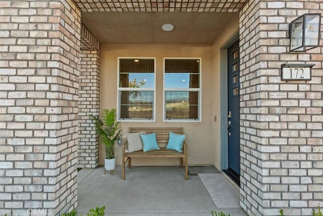 property entrance with stucco siding and brick siding