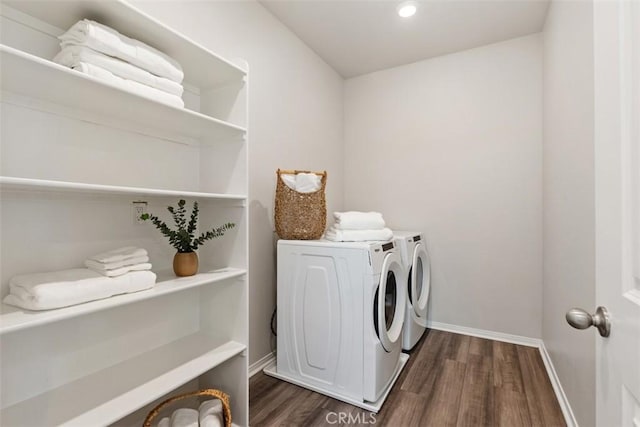 laundry room featuring dark wood finished floors, laundry area, baseboards, and washer and clothes dryer