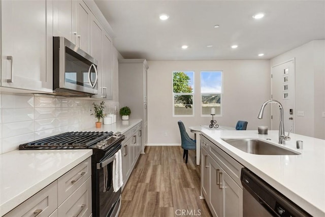 kitchen with a sink, decorative backsplash, appliances with stainless steel finishes, and light countertops