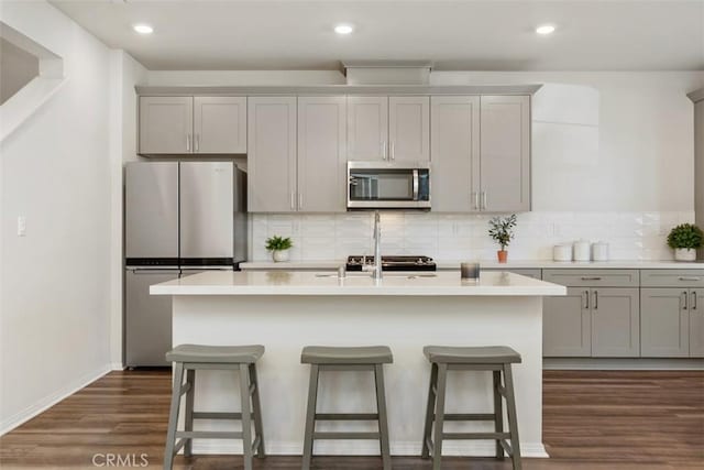 kitchen featuring dark wood finished floors, a breakfast bar, gray cabinets, and stainless steel appliances