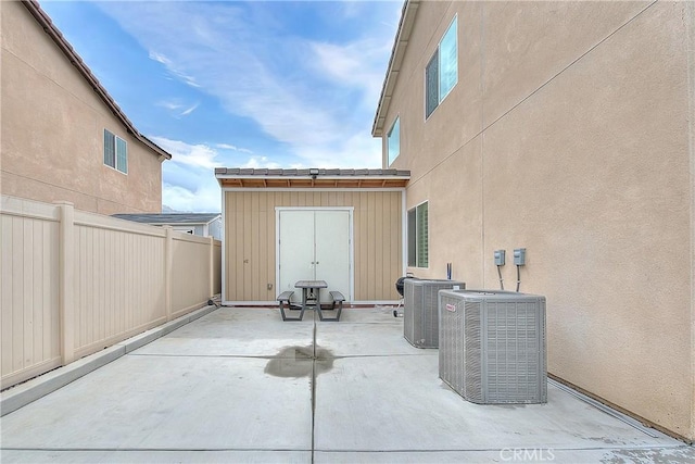 view of patio / terrace with an outbuilding, central AC, a storage shed, and fence