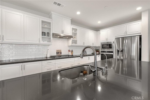 kitchen with visible vents, under cabinet range hood, appliances with stainless steel finishes, white cabinetry, and dark countertops