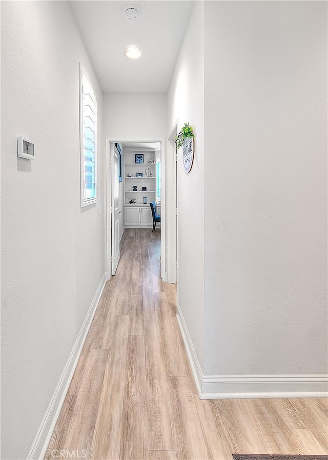 hallway featuring light wood-type flooring and baseboards