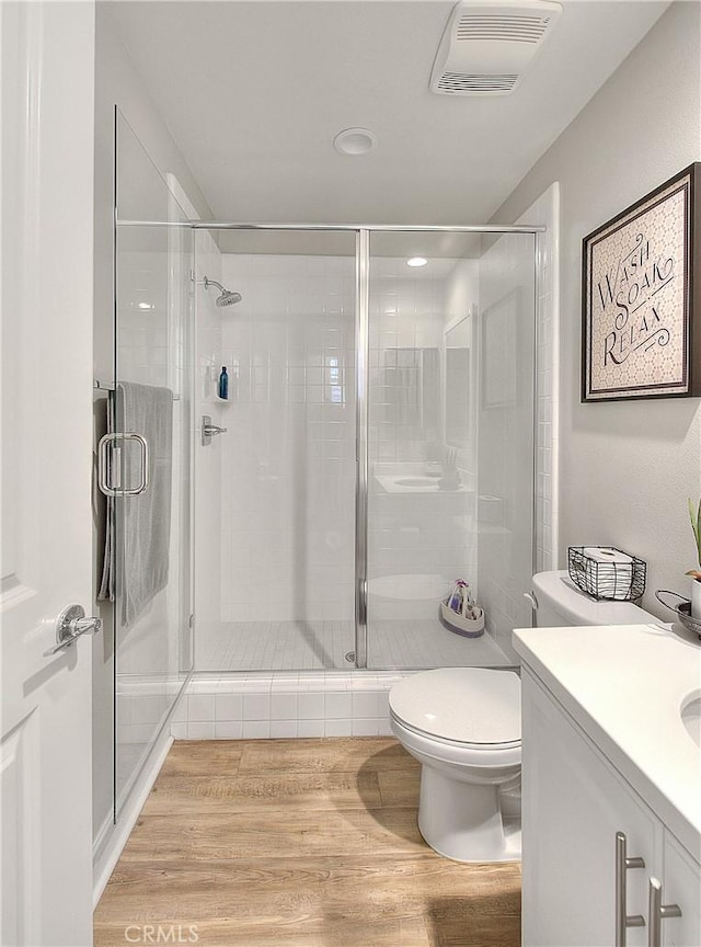 full bath featuring visible vents, toilet, a stall shower, wood finished floors, and vanity