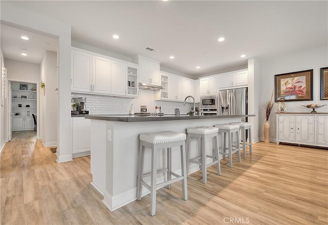 kitchen featuring visible vents, white cabinets, stainless steel appliances, and light wood-style flooring