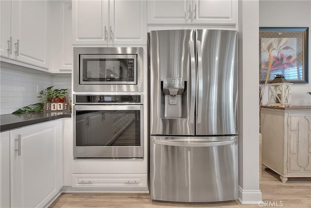 kitchen with white cabinets, light wood-style flooring, tasteful backsplash, and stainless steel appliances