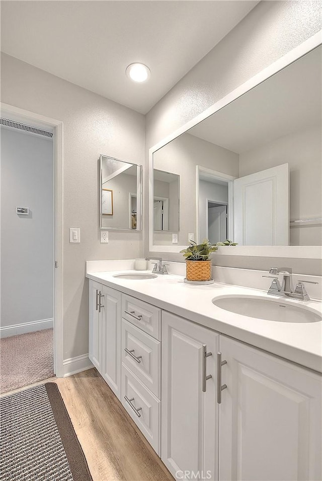 bathroom featuring double vanity, wood finished floors, baseboards, and a sink