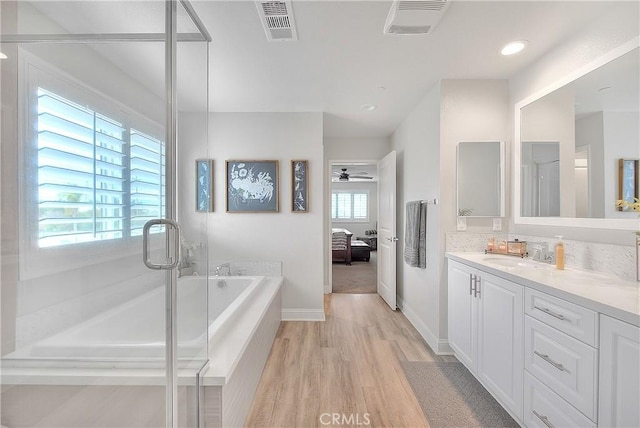 bathroom featuring visible vents, a garden tub, wood finished floors, connected bathroom, and vanity