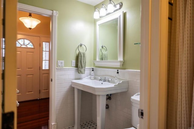 bathroom with wainscoting, tile walls, and toilet