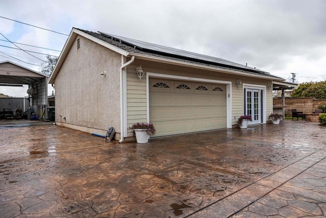 garage featuring a detached carport, concrete driveway, and roof mounted solar panels