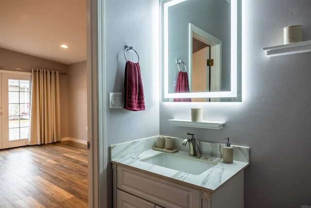 bathroom with vaulted ceiling, recessed lighting, vanity, and wood finished floors