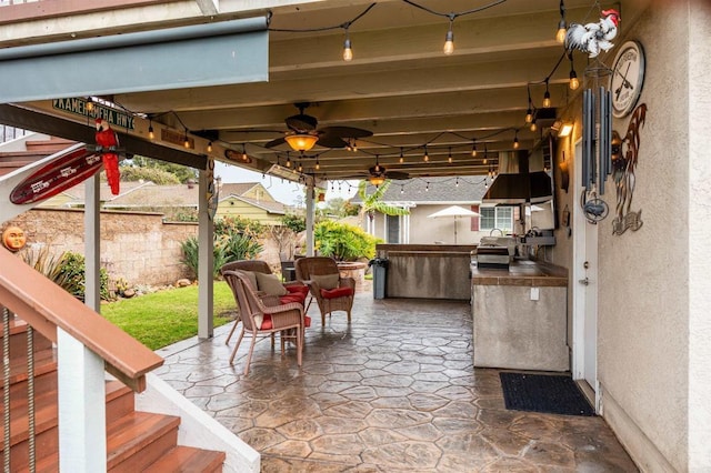 view of patio / terrace with a ceiling fan, a grill, fence, and an outdoor kitchen