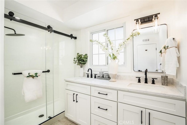 full bathroom featuring double vanity, visible vents, a stall shower, and a sink