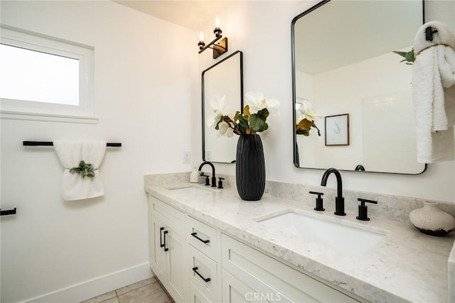 full bathroom featuring a sink, baseboards, double vanity, and tile patterned floors