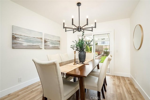 dining space featuring a notable chandelier, baseboards, and light wood-type flooring