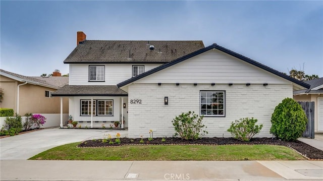 view of front of home featuring a chimney, brick siding, driveway, and a shingled roof