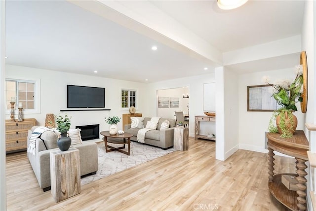 living area with recessed lighting, baseboards, a glass covered fireplace, and light wood finished floors