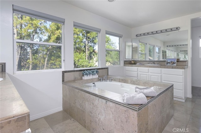 full bath with baseboards, a bath, and vanity