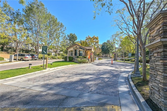 view of street with a gated entry and curbs