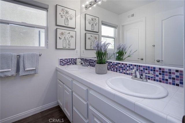 bathroom with tasteful backsplash, visible vents, baseboards, and a sink