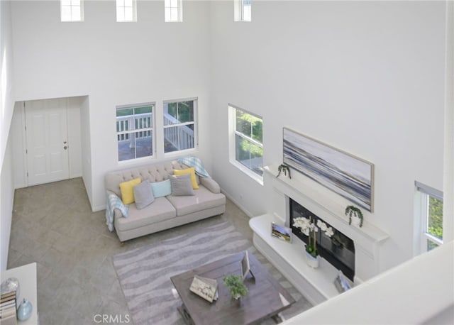 living area featuring a wealth of natural light, baseboards, and a towering ceiling